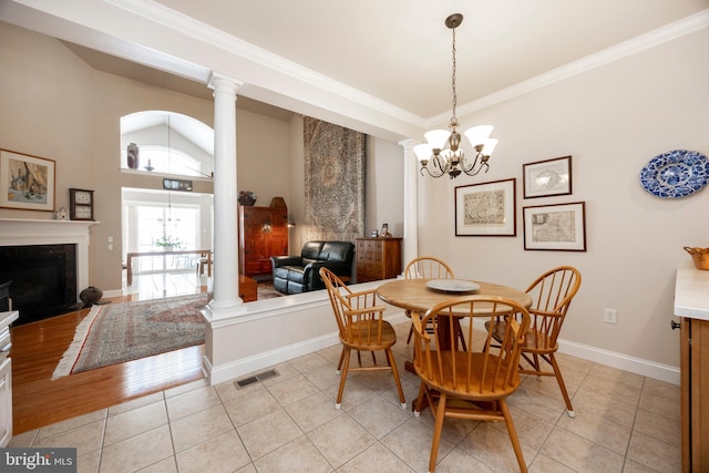 dining space featuring an inviting chandelier, light tile patterned floors, ornamental molding, and ornate columns