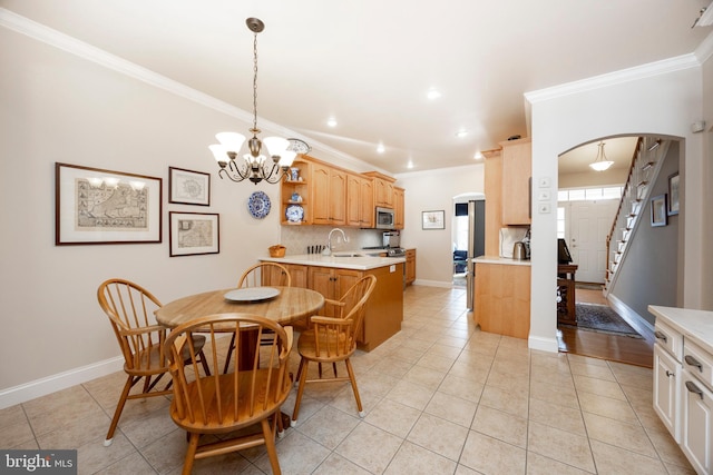 dining area featuring light tile patterned flooring, sink, an inviting chandelier, and crown molding