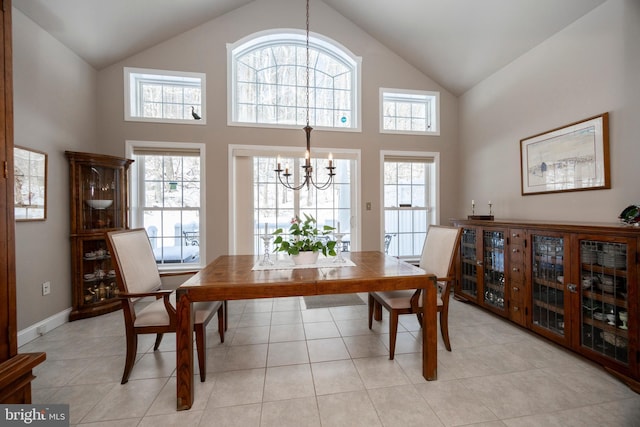 dining area with an inviting chandelier, light tile patterned flooring, and high vaulted ceiling