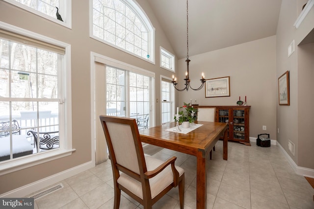 tiled dining space with high vaulted ceiling and a chandelier