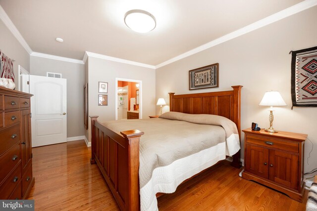 bedroom featuring ensuite bath, ornamental molding, and light hardwood / wood-style floors