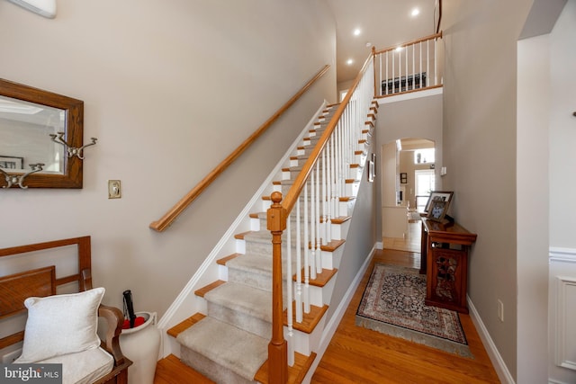 stairs featuring hardwood / wood-style floors and a high ceiling