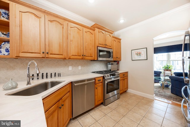 kitchen featuring sink, crown molding, light tile patterned floors, stainless steel appliances, and decorative backsplash