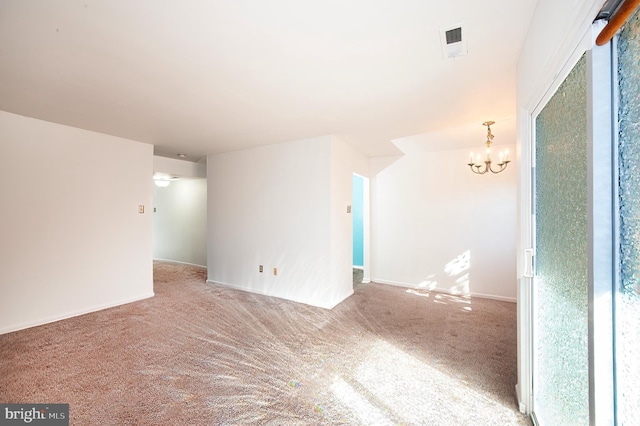 carpeted spare room with an inviting chandelier