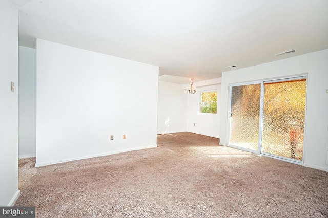 empty room featuring carpet flooring and a notable chandelier