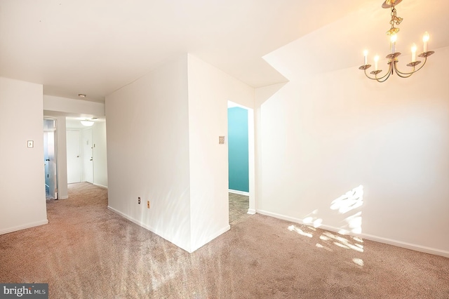 carpeted empty room featuring a chandelier