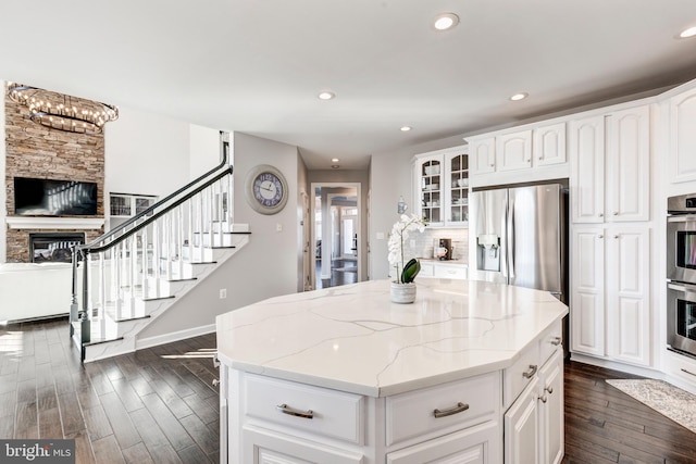 kitchen featuring light stone countertops, a center island, white cabinets, a fireplace, and appliances with stainless steel finishes