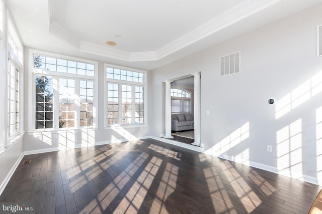 unfurnished sunroom featuring decorative columns and a tray ceiling