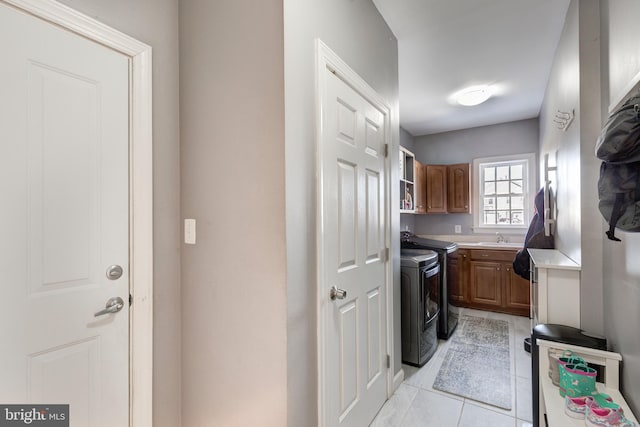 clothes washing area with sink, cabinets, independent washer and dryer, and light tile patterned floors