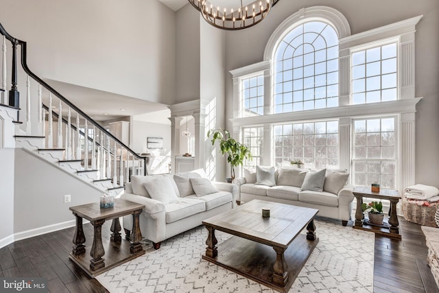 living room featuring a high ceiling, hardwood / wood-style flooring, an inviting chandelier, and decorative columns