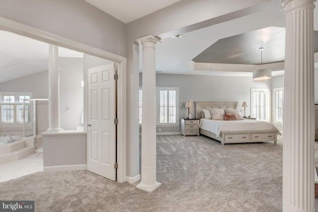 carpeted bedroom with a notable chandelier, connected bathroom, a raised ceiling, and ornate columns