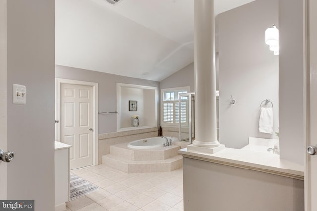 bathroom featuring vanity, tiled tub, vaulted ceiling, and tile patterned floors