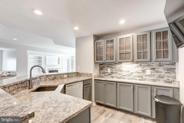 kitchen featuring sink, dishwasher, gray cabinetry, and light stone countertops