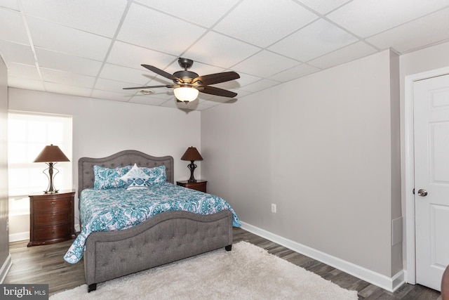 bedroom featuring a drop ceiling, hardwood / wood-style floors, and ceiling fan