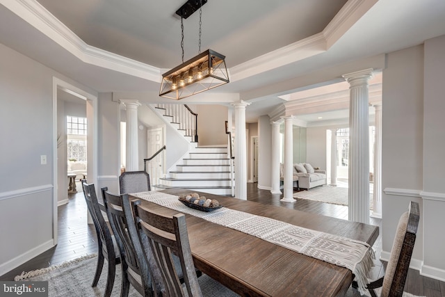 dining space with wood-type flooring, ornamental molding, a chandelier, and a tray ceiling