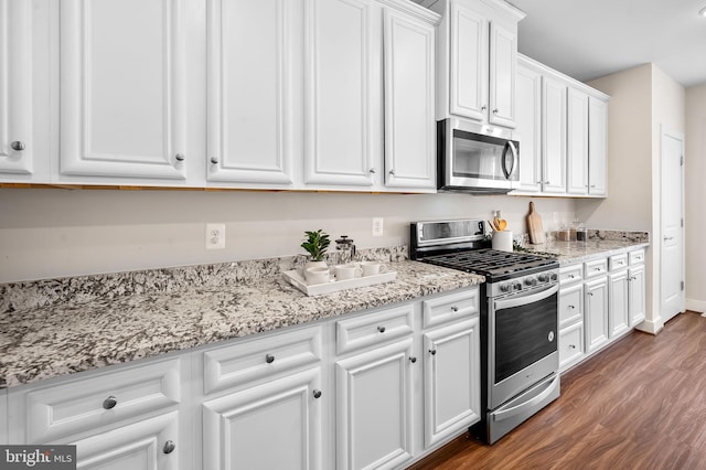 kitchen with light stone countertops, dark hardwood / wood-style flooring, white cabinetry, and stainless steel appliances