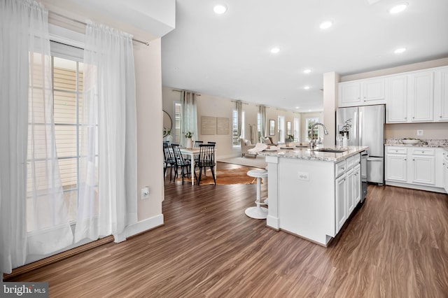 kitchen featuring dark wood-type flooring, a center island with sink, white cabinets, sink, and stainless steel appliances