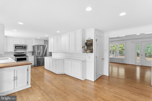 kitchen featuring white cabinets, light hardwood / wood-style floors, stainless steel appliances, and tasteful backsplash