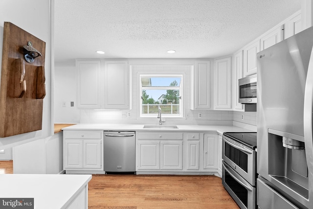 kitchen featuring sink, white cabinets, stainless steel appliances, and a textured ceiling