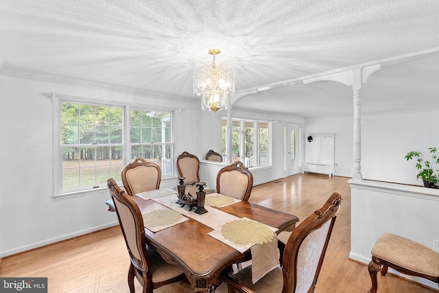 dining space featuring crown molding, ornate columns, baseboard heating, light wood-type flooring, and a chandelier