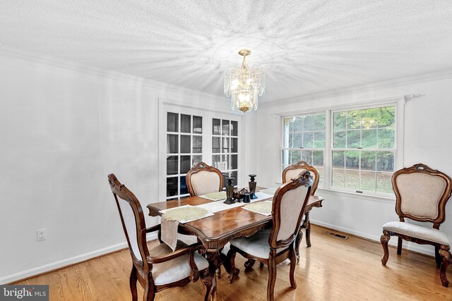 dining area featuring light wood-type flooring, ornamental molding, and a chandelier