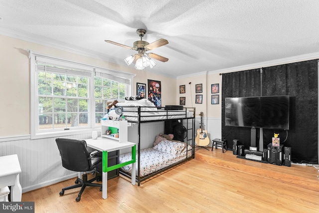 bedroom with ceiling fan, wood-type flooring, a textured ceiling, and ornamental molding