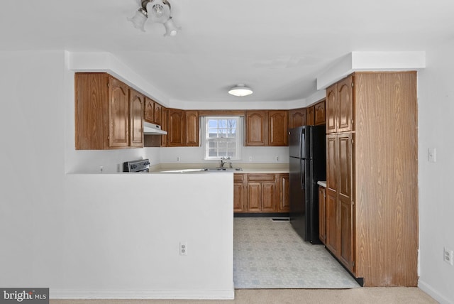 kitchen with black refrigerator, kitchen peninsula, stainless steel range, and sink