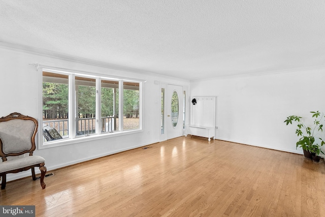 interior space with crown molding, light hardwood / wood-style floors, and a textured ceiling