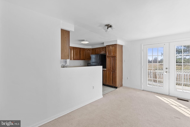 kitchen featuring french doors, light colored carpet, and black fridge