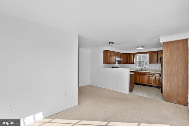 kitchen featuring black refrigerator, light colored carpet, and sink