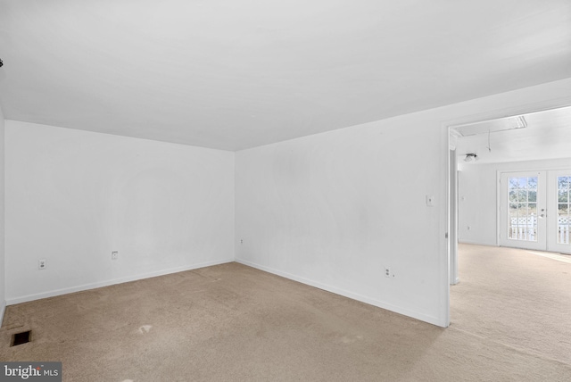 spare room with french doors and light colored carpet