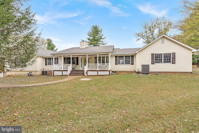 view of front facade featuring central AC, covered porch, and a front yard