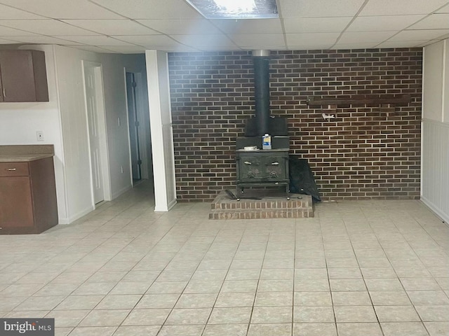 unfurnished living room featuring a wood stove and brick wall