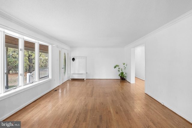 empty room with light hardwood / wood-style floors, ornamental molding, and a textured ceiling