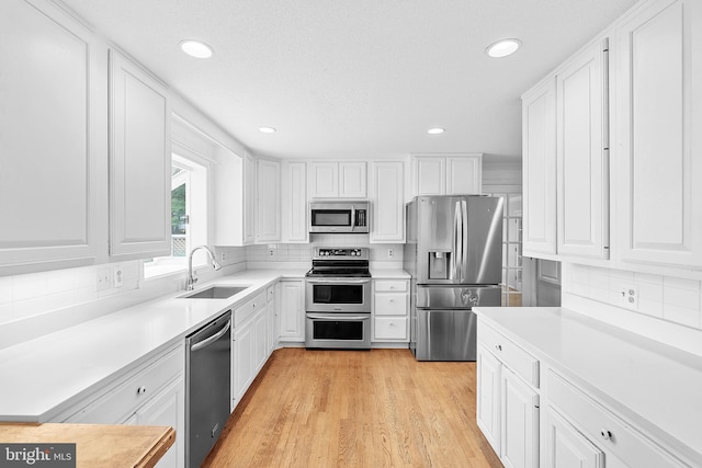 kitchen featuring white cabinets, appliances with stainless steel finishes, light hardwood / wood-style floors, and sink