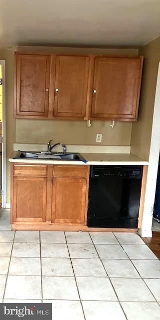 kitchen featuring light tile patterned floors, black dishwasher, and sink