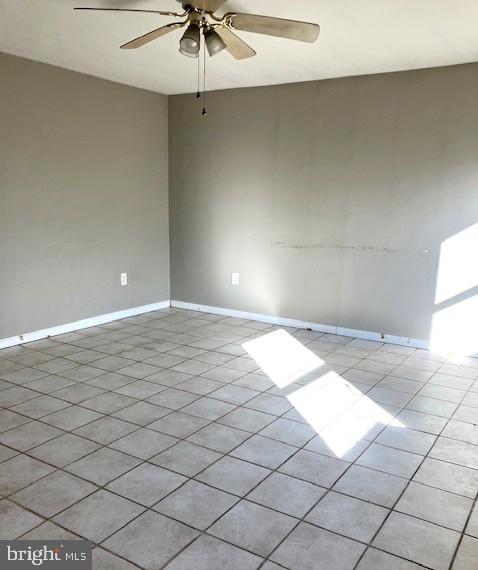 spare room with ceiling fan and light tile patterned flooring