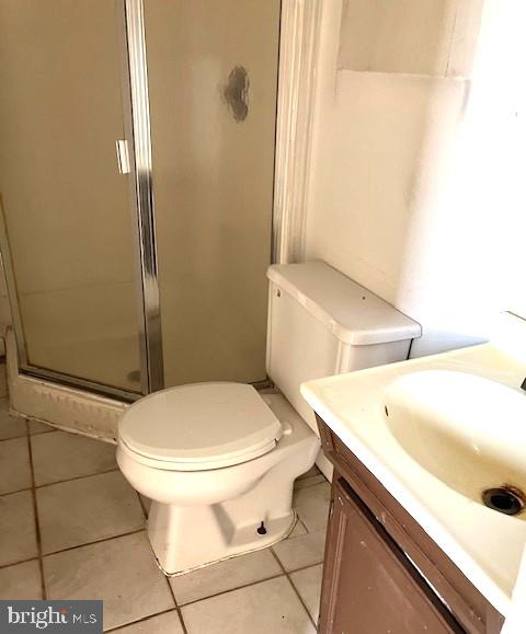 bathroom featuring toilet, vanity, tile patterned floors, and walk in shower