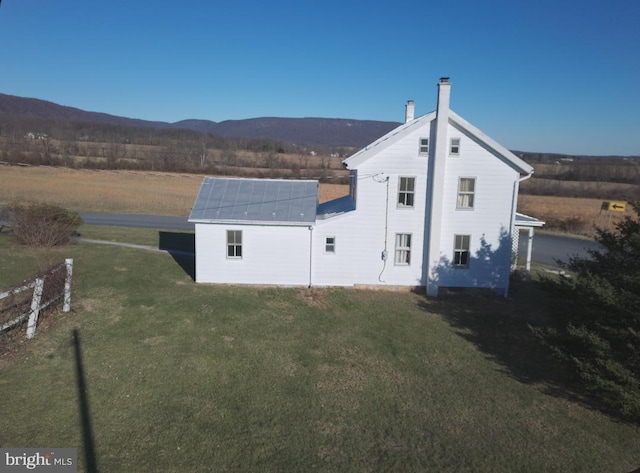 back of house with a mountain view and a lawn