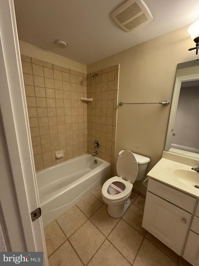 full bathroom with tile patterned flooring, vanity, tiled shower / bath combo, and toilet