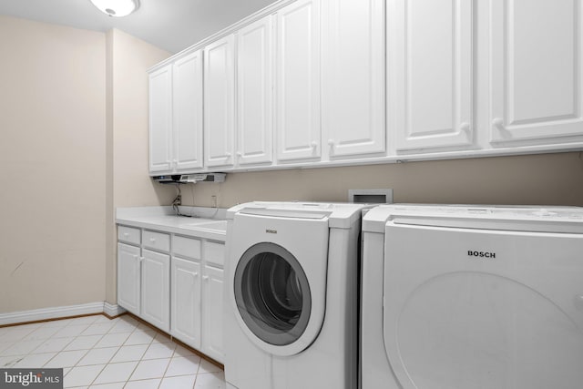 clothes washing area with cabinets, washing machine and clothes dryer, and light tile patterned floors