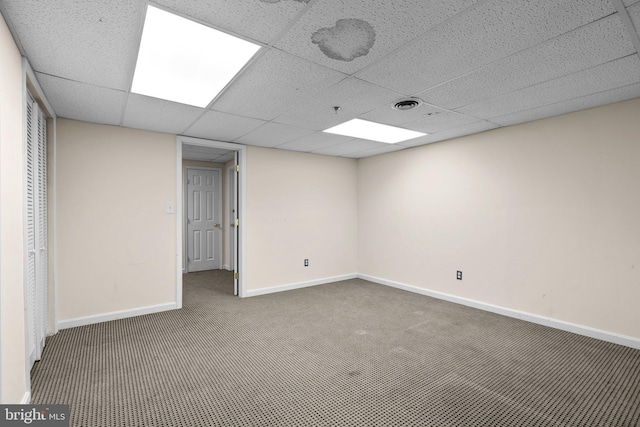 unfurnished room featuring a drop ceiling and dark colored carpet