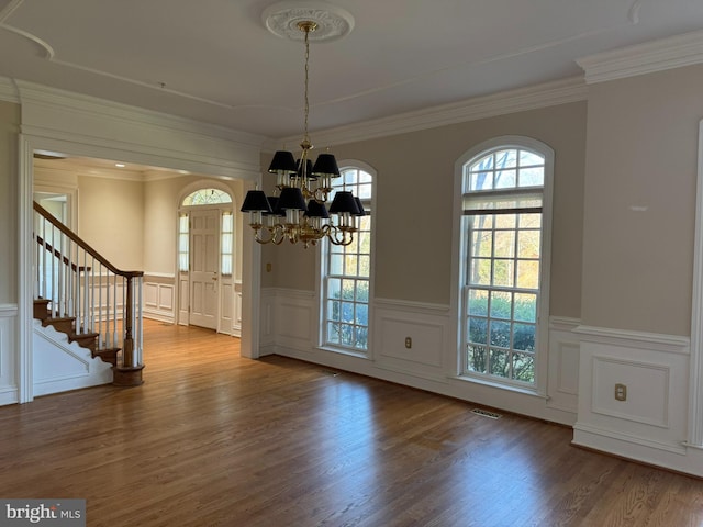 unfurnished dining area with ornamental molding, a chandelier, and hardwood / wood-style floors