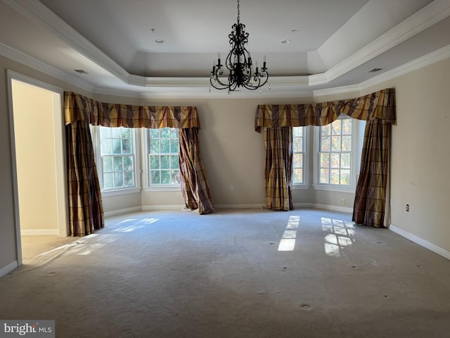 carpeted spare room with a raised ceiling, ornamental molding, and a healthy amount of sunlight