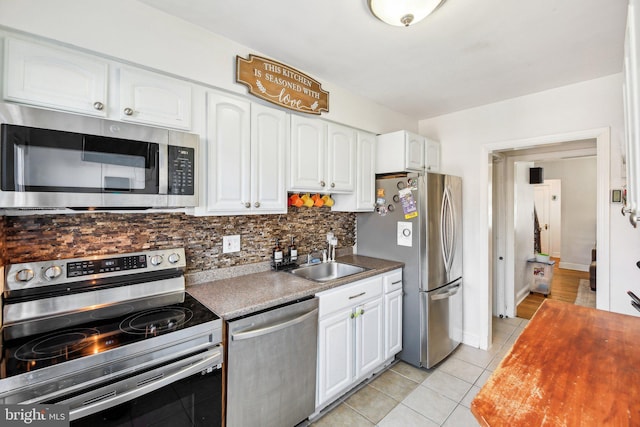 kitchen featuring white cabinets, sink, light tile patterned floors, tasteful backsplash, and stainless steel appliances