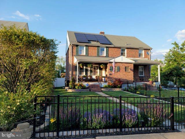 view of front of house with a front yard, solar panels, and covered porch