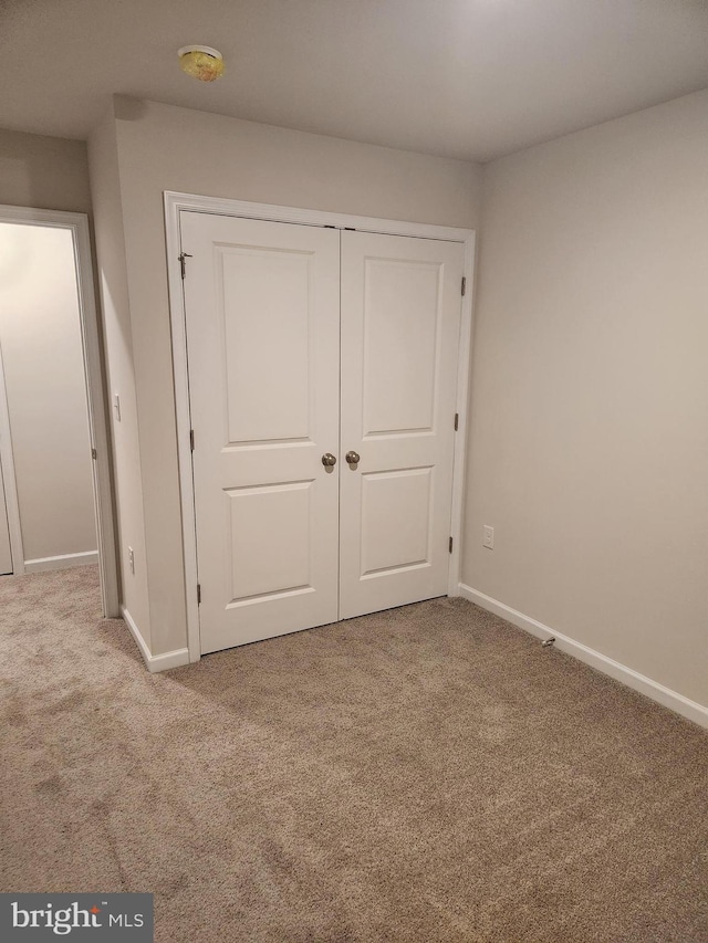 unfurnished bedroom featuring a closet and light colored carpet