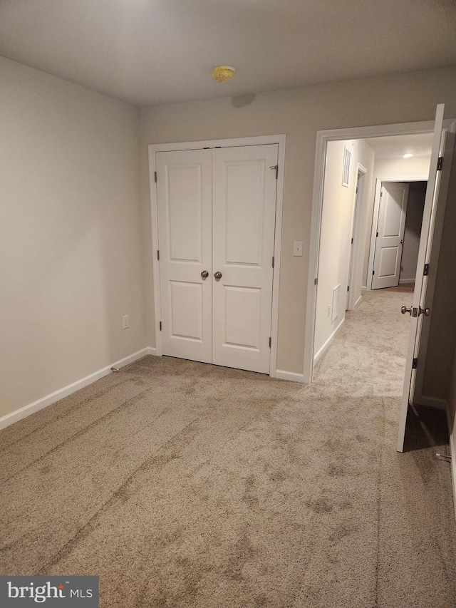 unfurnished bedroom featuring light carpet and a closet