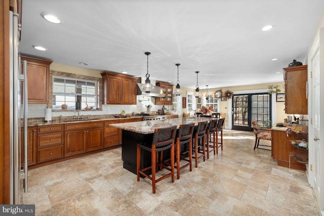 kitchen with pendant lighting, a kitchen bar, stove, a center island, and light stone countertops