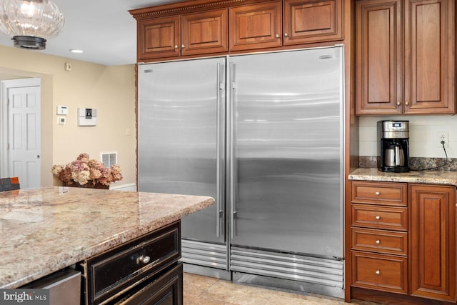 kitchen with light stone countertops, built in fridge, and light tile patterned floors